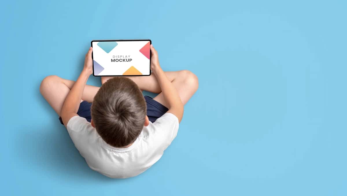 Planshet maketining tepadan ko‘rinishini ushlab turgan bola | Boy holding tablet mockup top view 1