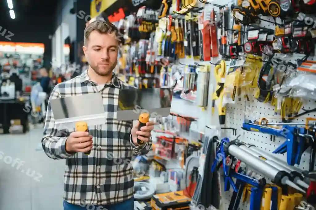 Erkak mijoz zamonaviy asboblar do'konida trowellarni tanlaydi. | Male customer modern hardware store chooses trowels
