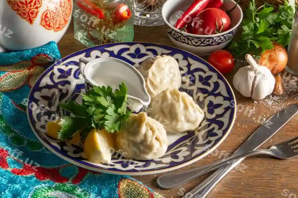 An'iyviy o'zbek qo'lma manti guruch qırmızı va piyoz bilan to'ldirilgan, sharqaviy souse (smetana, tuz, qalap, sarimsoqdan tayyorlangan) bilan xizmat qilinishadi. An'iyviy o'zbek naqshli disk. | Traditional uzbek hand made manti steamed with minced lamb onion filling with oriental sauce made sour cream salt pepper garlic plate with traditional uzbek pattern 2