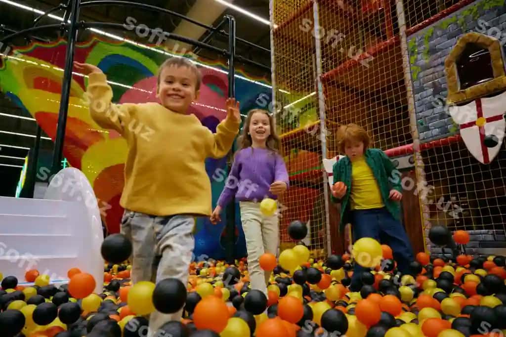 Baxtli kichik bolalar kinder sadkasining ichki o'yin maydonida vaqt o'tkazmoqda. | Cheerful little children spending time daycare indoor playground