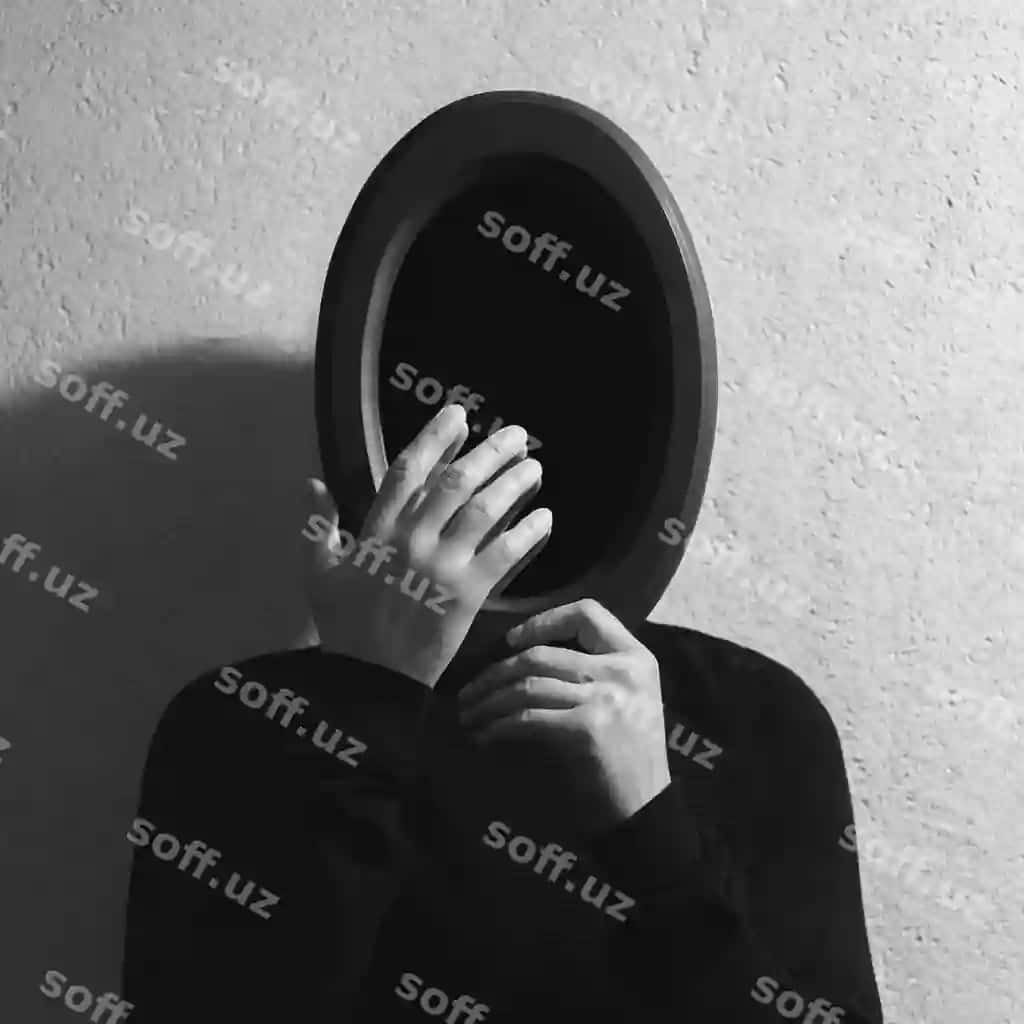 Qora oq studio portreti yosh erkak oval ayna tutgan, yuzini qo'l bilan bog'gan, oldida ayna, qora uchlar fon, matalaksiz kulrang devor. | Black white studio portrait young man holding oval mirror face touching with hand front mirror black hole background textured grey wall