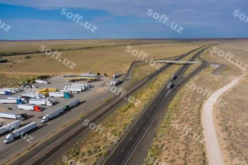 Gorizontal panoramali yuk mashinalari shtatlararo avtomagistralning Arizona cho'li AQSH yaqinidagi dam olish joyini to'xtatadi | Horizontal panorama trucks stop rest area near interstate highway desert arizona usa