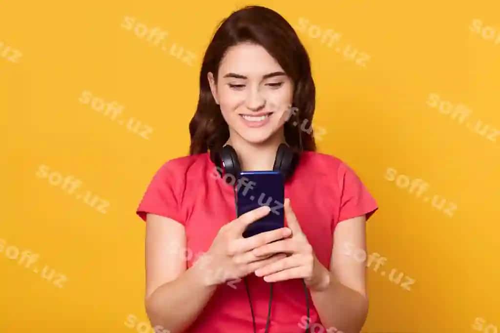 Qora sochli ayol naushnik taqgan, kommandal kiyim kiygan, musbat emotsiyalar bor, smartfon tutgan. | Woman with dark hair having headphones wearing casual attire has positive emotions holding smart phone hands